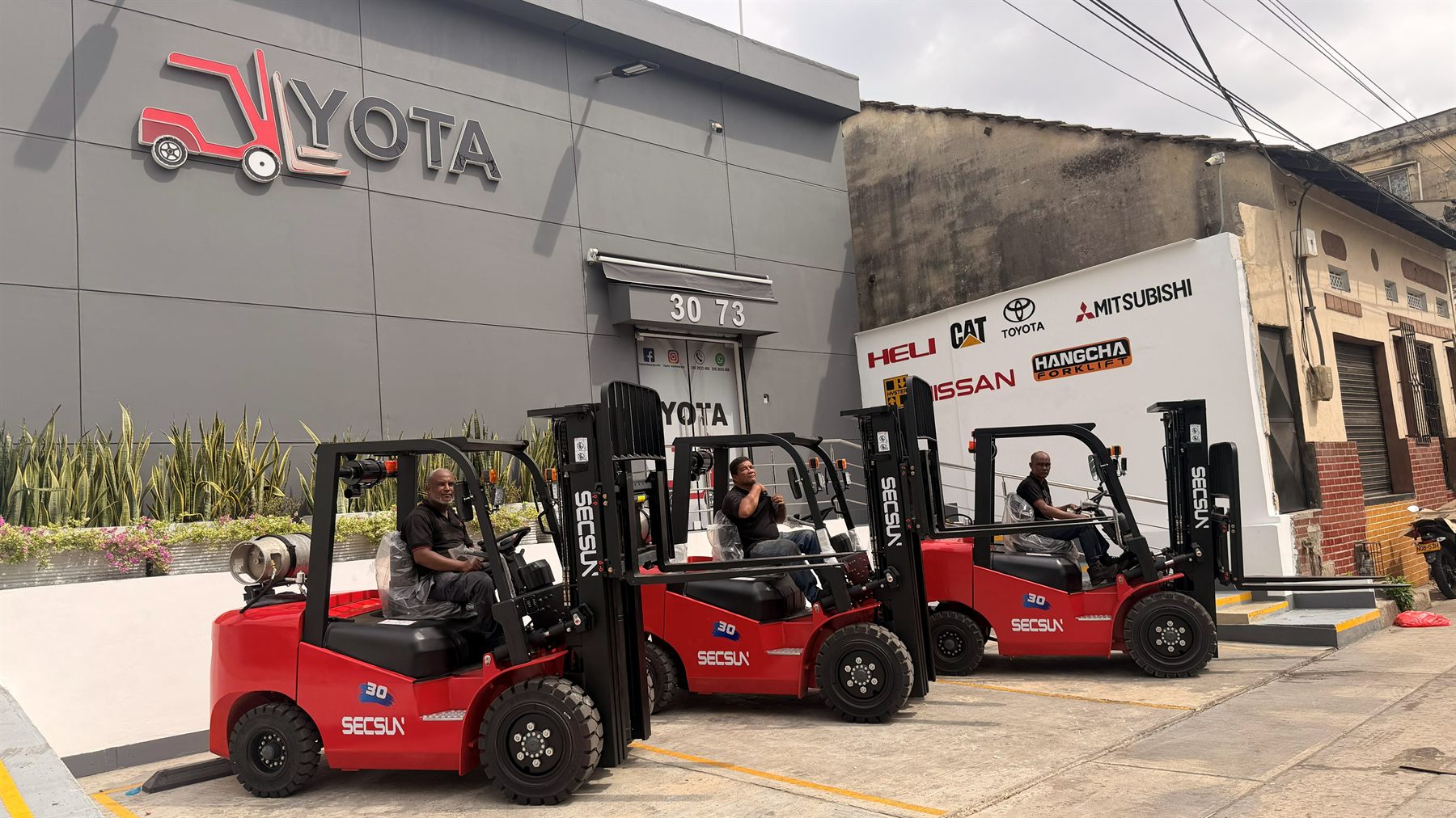 Tres montacargas Secsun FG30 rojos, nuevos, frente a la bodega de YOTA Montacargas en Barranquilla